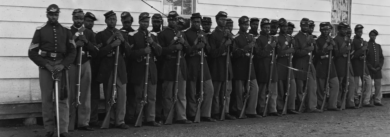 Photograph of Washington, 1862-1865, view of the defenses of Washington. Shows 27 African Americans in two lines with rifles resting on the ground.