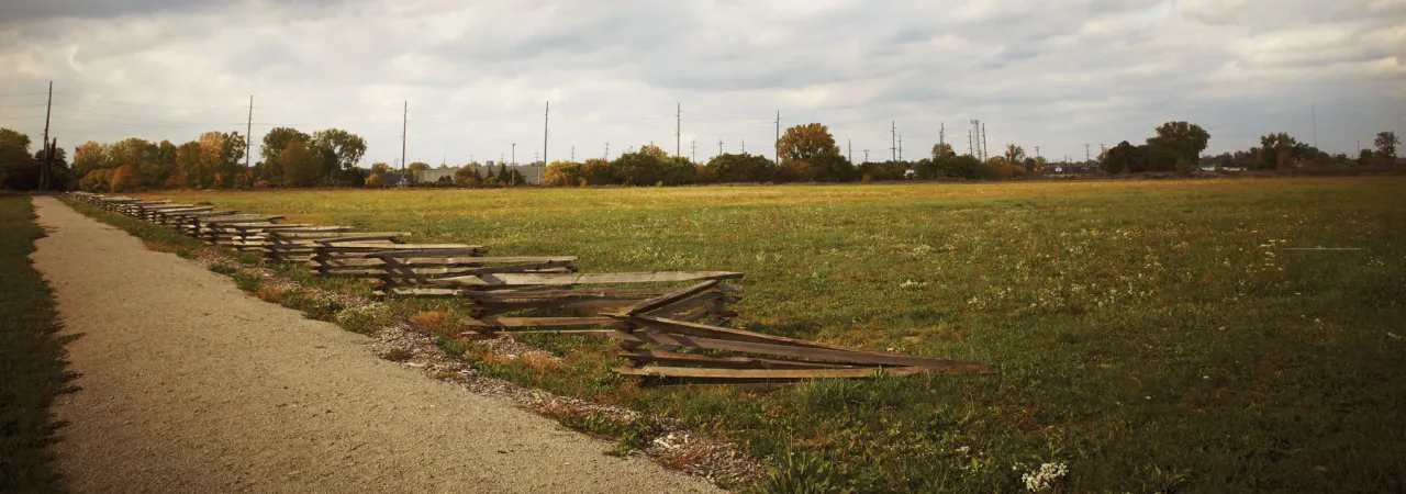 Snake Rail Fence with a dirt road and field, with a full sky of puffy white clouds 