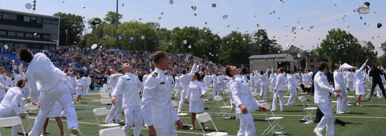 Graduates of the U.S. Merchant Marine Academy toss their caps in the air
