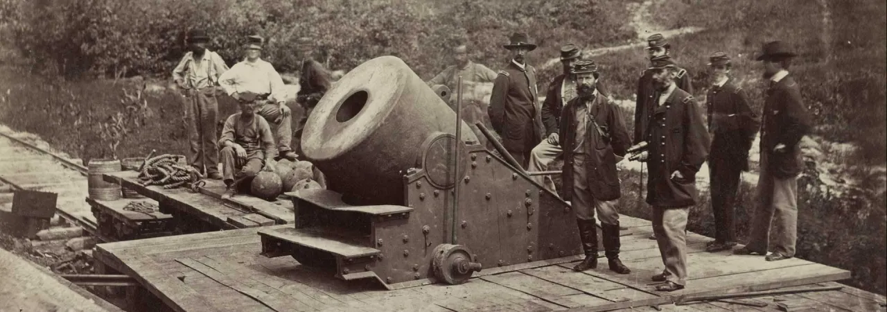 Photograph of soldiers standing in front of a cannon