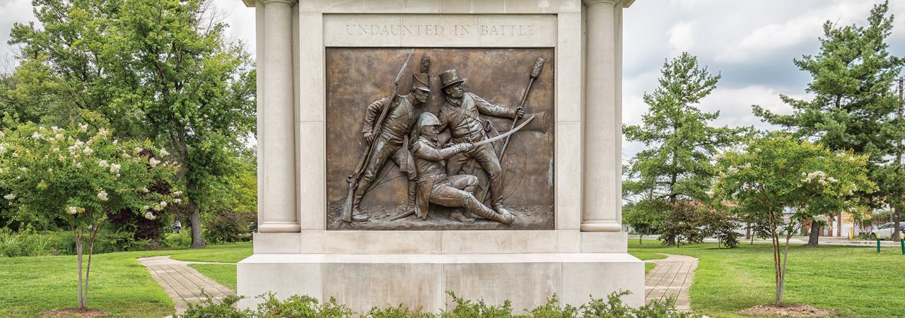 Stone memorial with a bronze bas-relief of three military officers