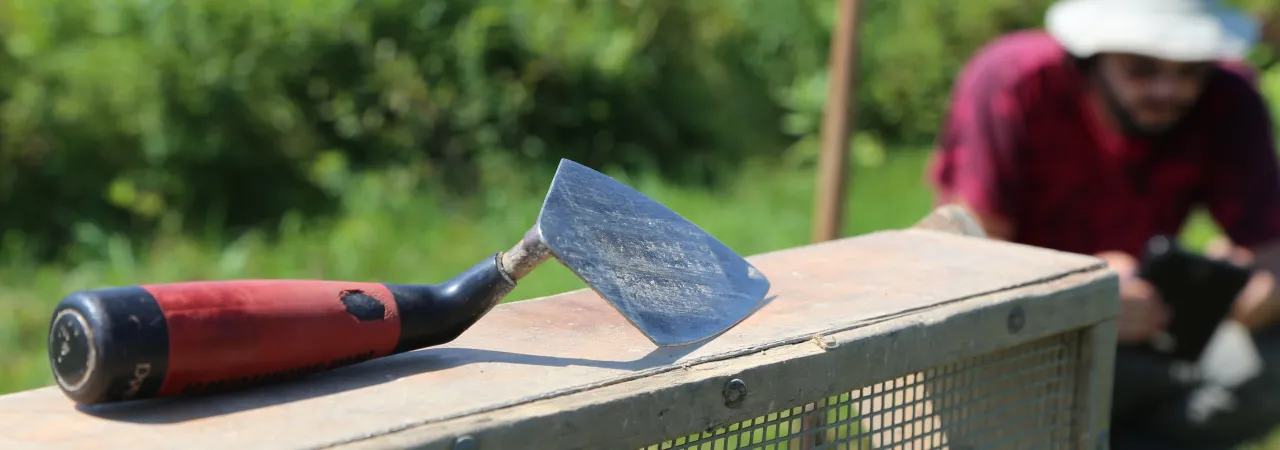 Photograph of a trowel at Saratoga Battlefield with an archaeologist