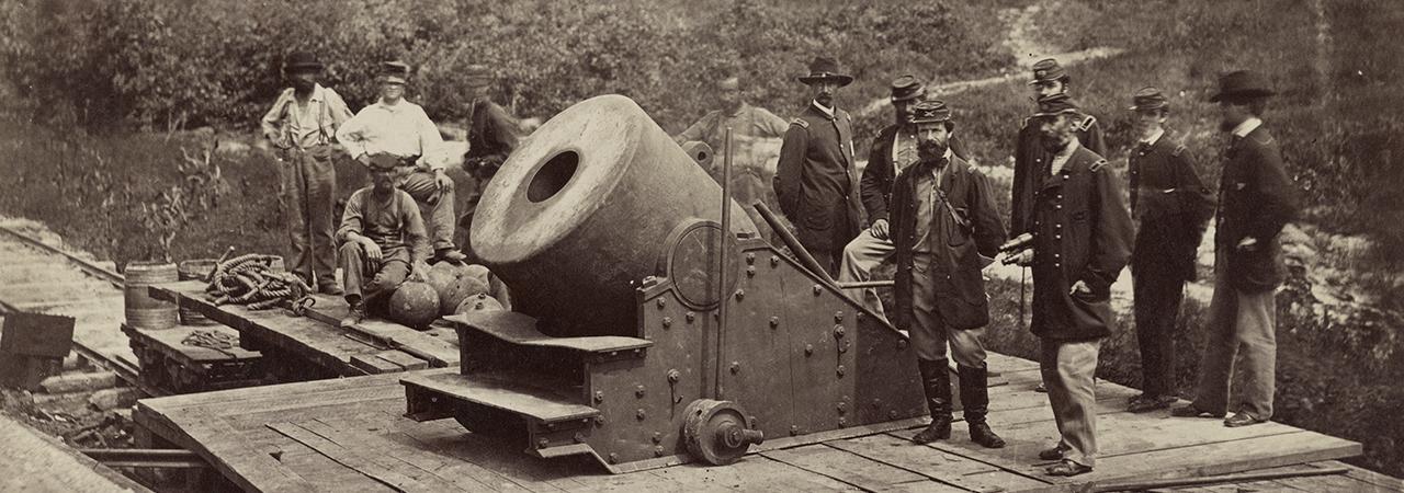 Photograph of soldiers standing in front of a cannon