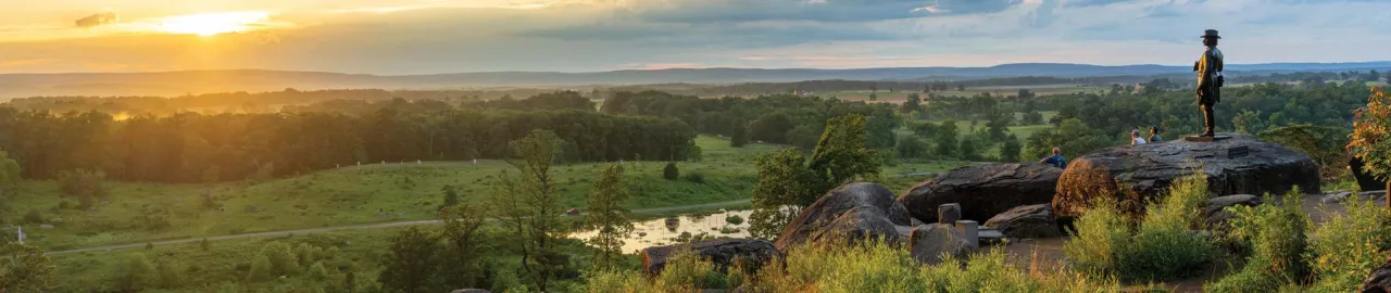 A couple sits on the rocks at Little Round Top at sunset