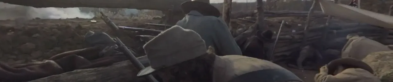 Photograph of a soldier crouching in front of a barrier with his gun