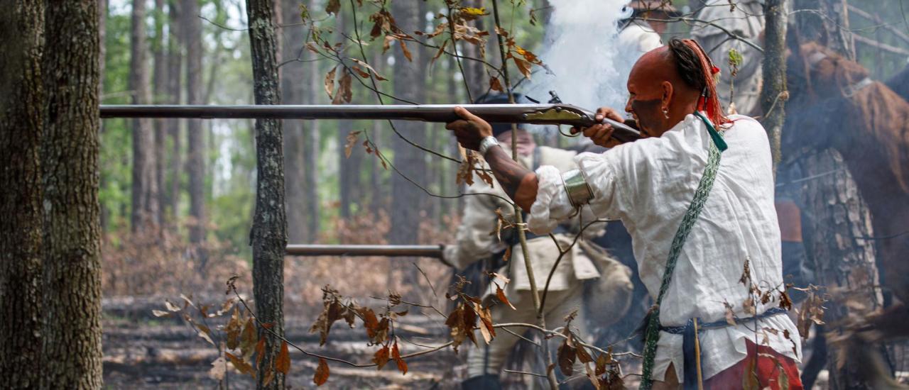 A Catawba reenactor aiming a rifle