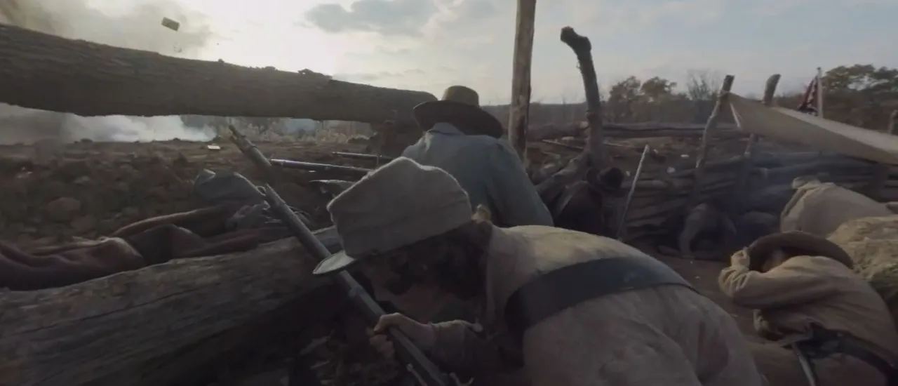 Photograph of a soldier crouching in front of a barrier with his gun