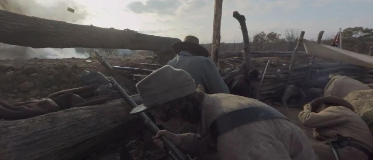 Photograph of a soldier crouching in front of a barrier with his gun