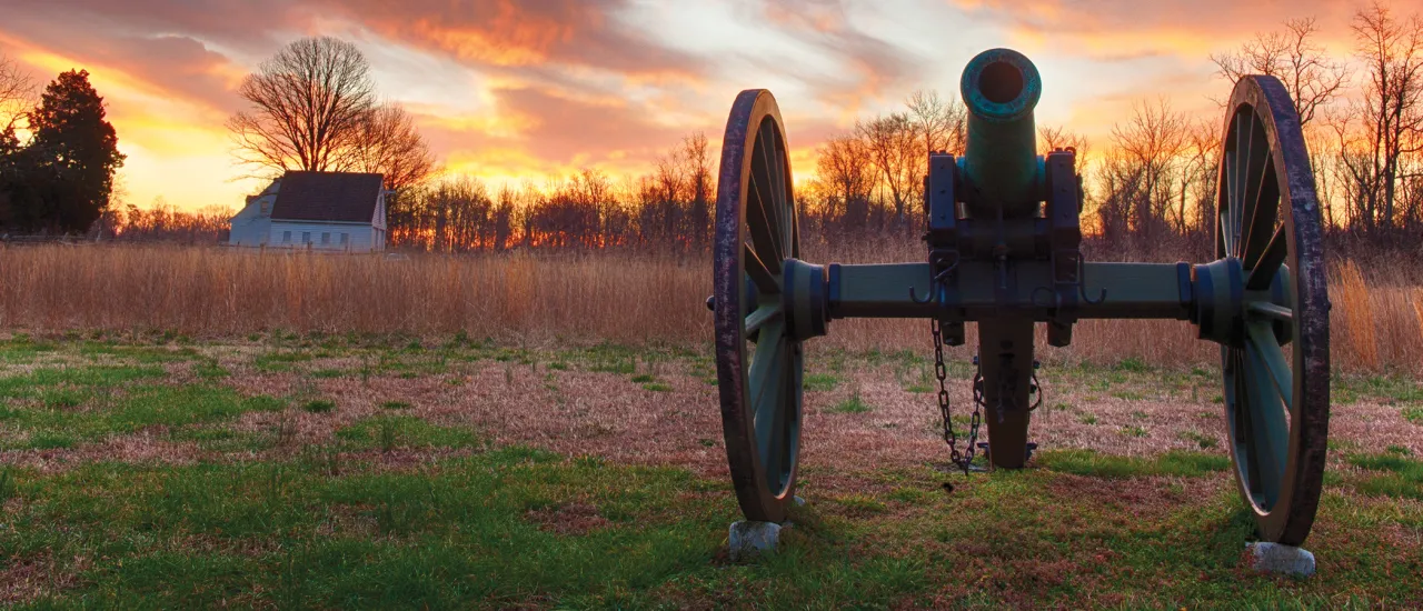 Photograph of a cannon with a vibrant sunset in the background