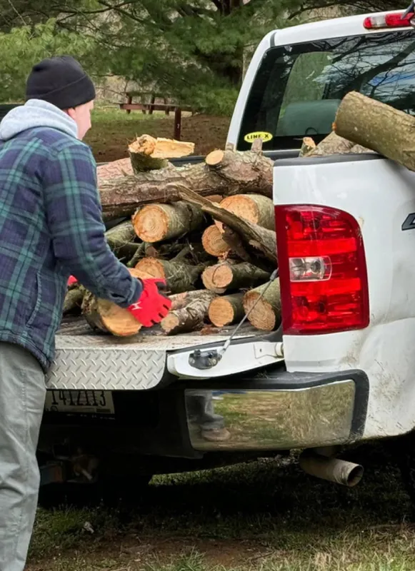 Volunteers unload wood from a white pickup truck