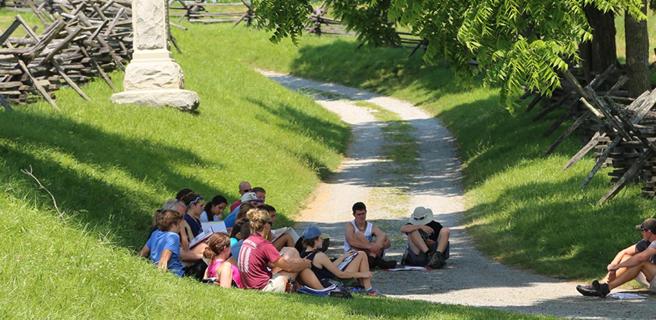 This is an image of a tour group sitting on the Antietam battlefield. 