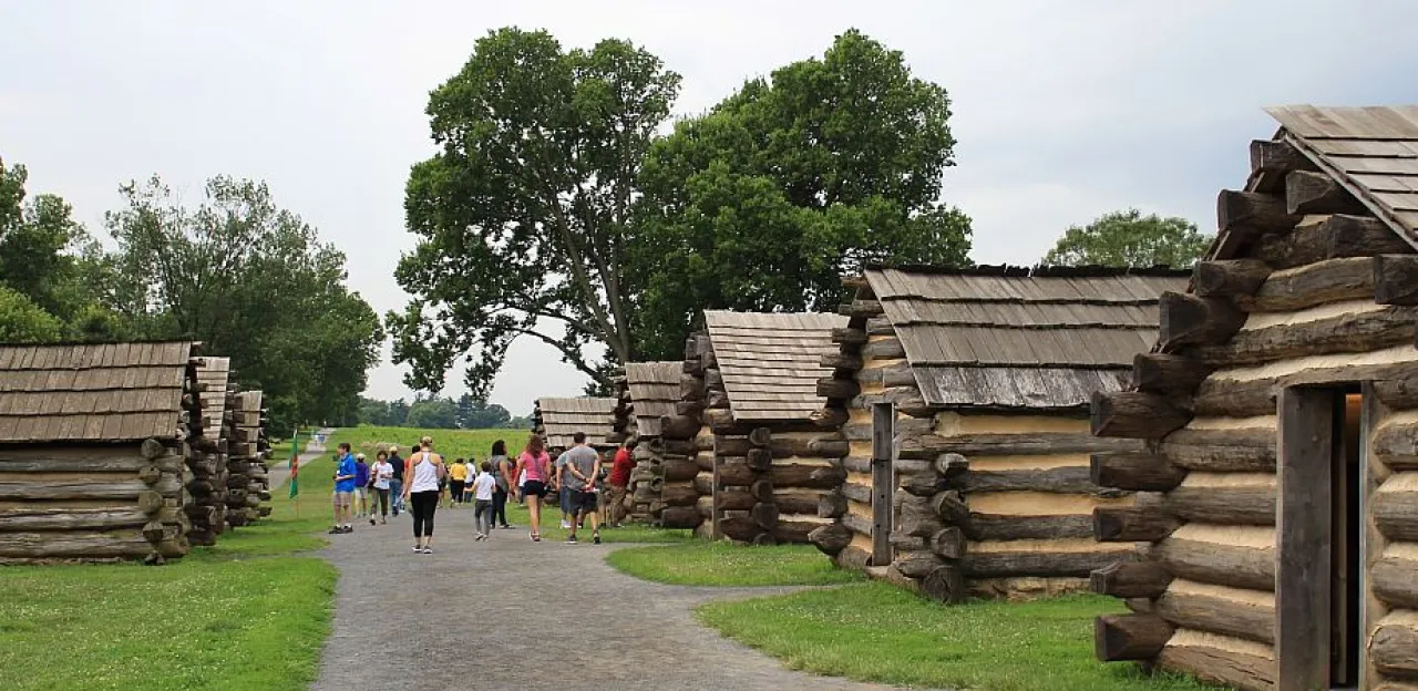 People walking down a path between log cabins