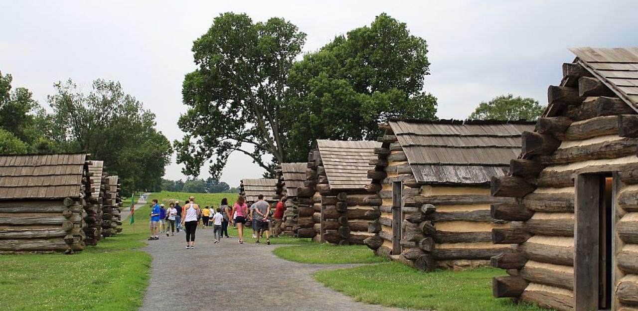 People walking down a path between log cabins