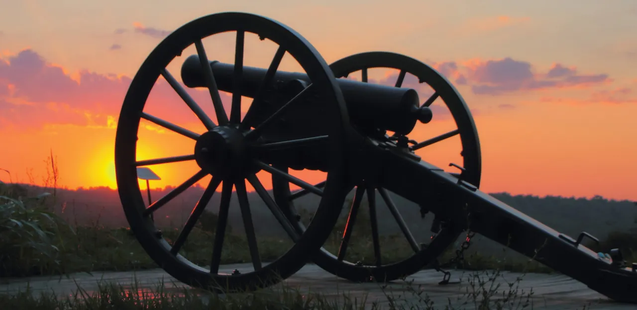 This is an image of a cannon resting in Lexington, Kentucky during a vibrant sunset. 