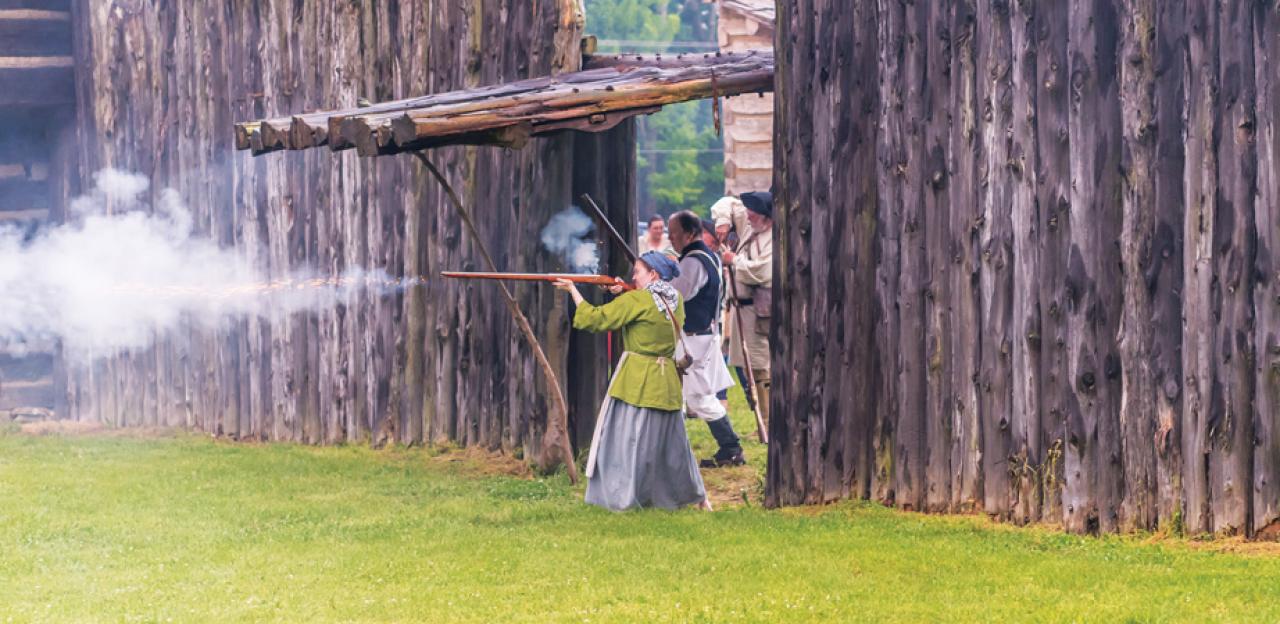 This is an image of a woman firing a gun at Logan's Fort. 