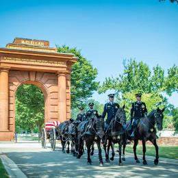 A funeral service passes through McClellan Arch at Arlington National Cemetery, Arlington, Va.