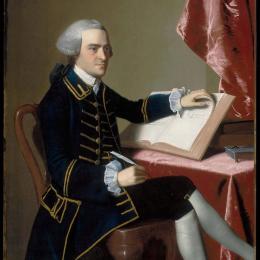 Portrait of a man sitting at a writing desk holding a quill pen and a book.