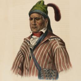 A Native American man wear a green cap and a red and white striped shirt. 
