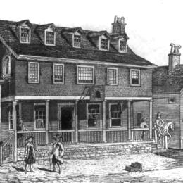 Black and white drawing of a colonial-era building with a porch on a cobble stone street on which several gentlemen stand
