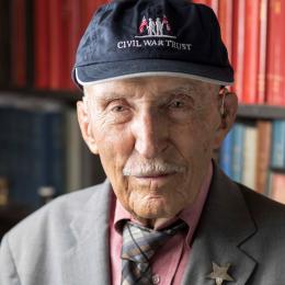 Older man wearing a Civil War Trust baseball cap, gray jacket, red shirt, and plaid tie.