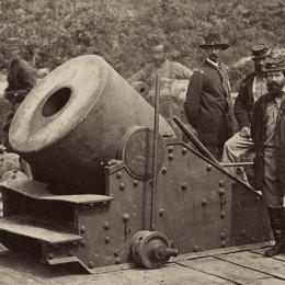 Photograph of soldiers standing in front of a cannon