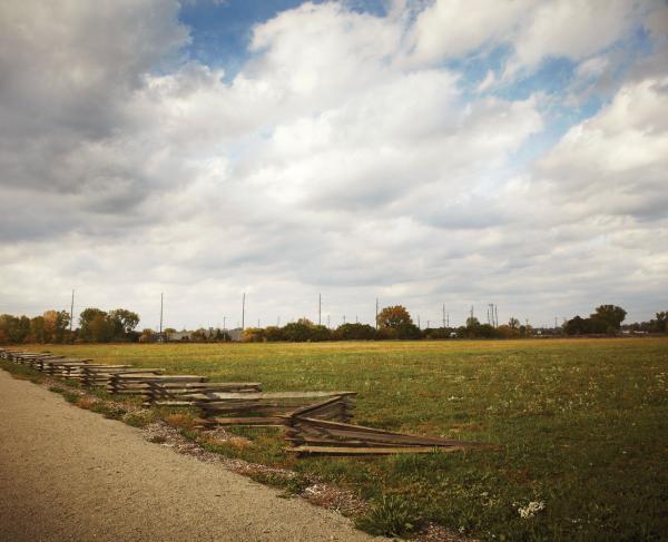 Snake Rail Fence with a dirt road and field, with a full sky of puffy white clouds 