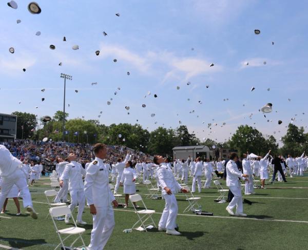 Graduates of the U.S. Merchant Marine Academy toss their caps in the air