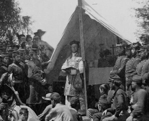 Photograph of a chaplain preaching to soldiers in a camp