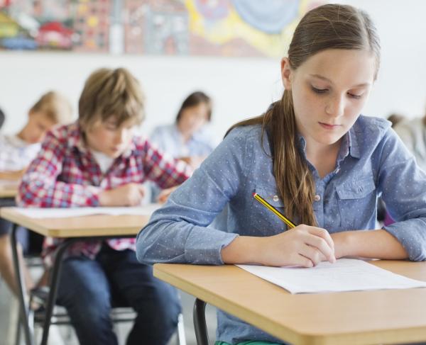 This is an image of middle school students taking a test while sitting at their desks. 