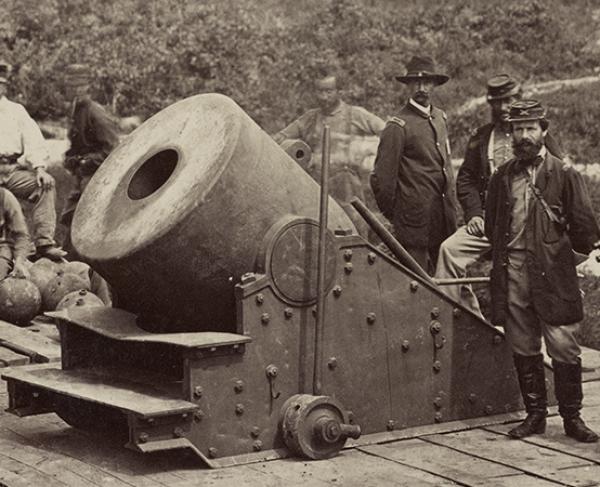 Photograph of soldiers standing in front of a cannon