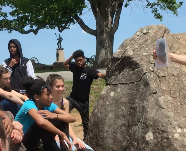 This is an image of a tour guide presenting to a group at a battlefield. 