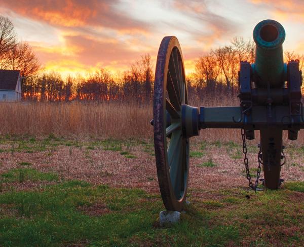 Photograph of a cannon with a vibrant sunset in the background