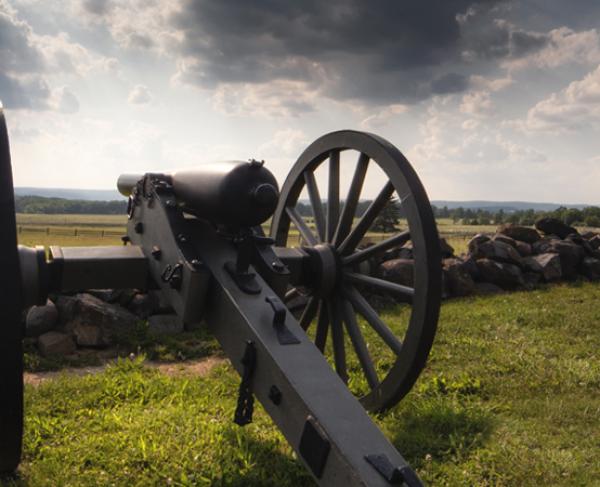 This photograph depicts a cannon resting on a battlefield. 
