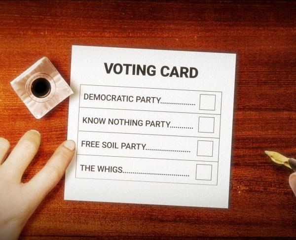 A person's hands preparing to vote on a voting card labeled with several political parties.