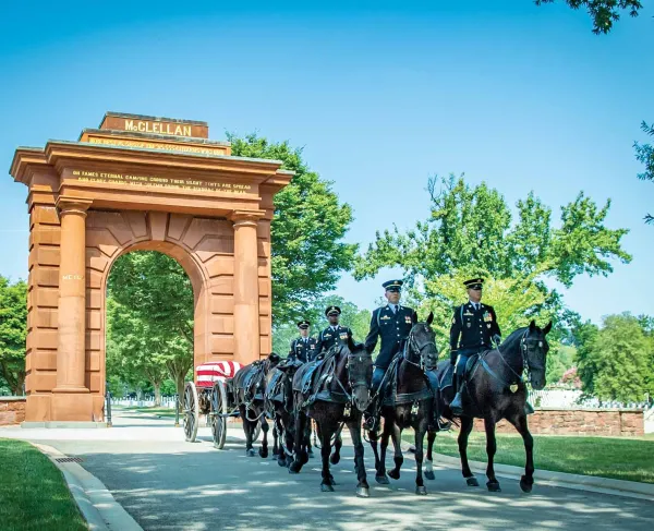 A funeral service passes through McClellan Arch at Arlington National Cemetery, Arlington, Va.