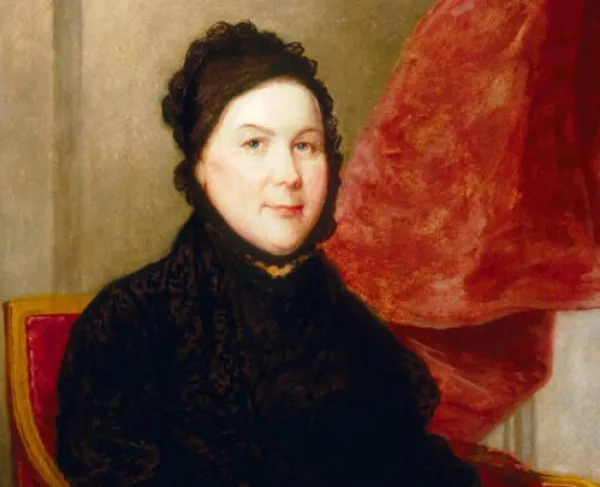 Image shows portrait of Catharine Greene as an older woman wearing a black dress, sitting at chair in front of red curtains. 