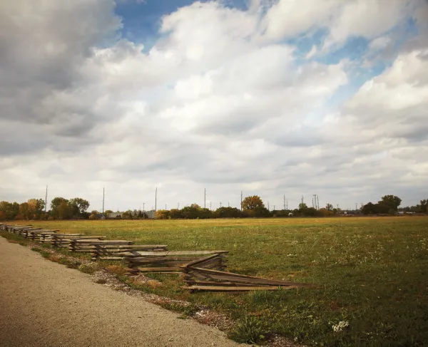 Snake Rail Fence with a dirt road and field, with a full sky of puffy white clouds 