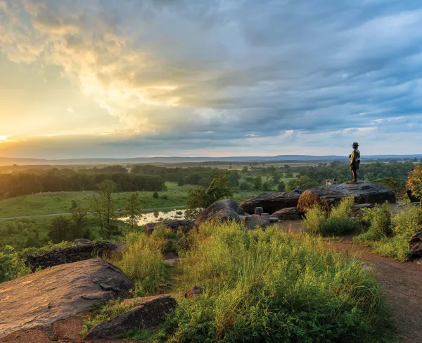 A couple sits on the rocks at Little Round Top at sunset