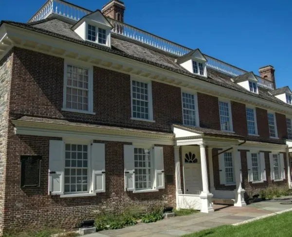 Colonial era 2-story red brick manor house with 11 windows and 3 dormer windows trimmed in white.