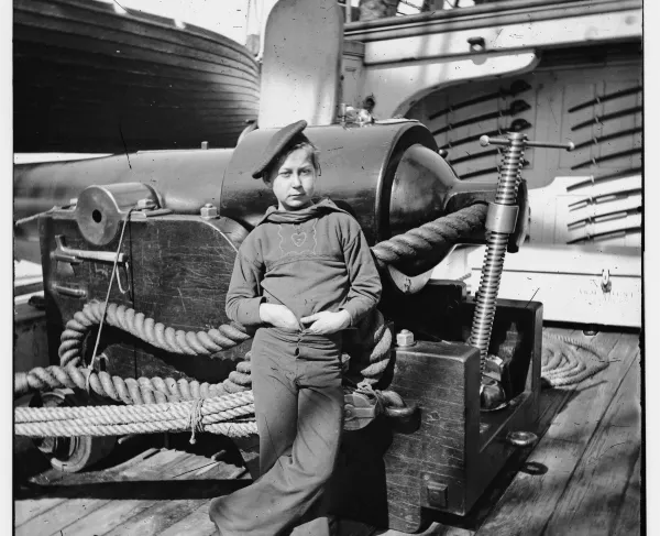 Civil War-era photograph of a young sailor standing beside a large naval gun aboard the USS New Hampshire off Charleston, South Carolina.