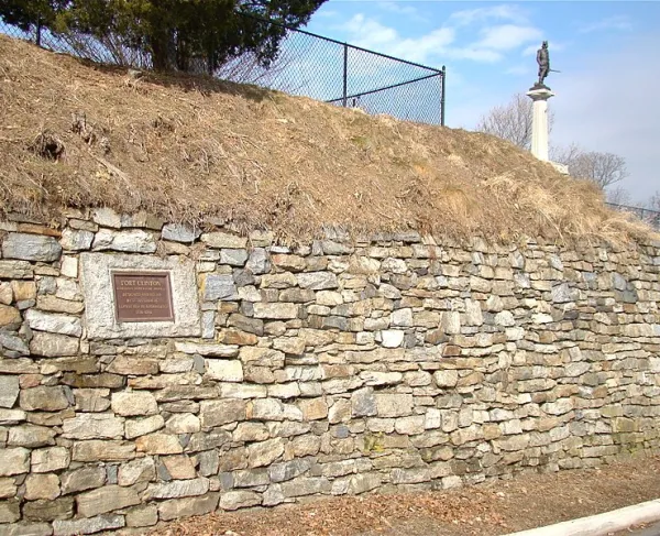 Stone remains of Fort Clinton (Fort Arnold) with a monument of a soldier in the background. 