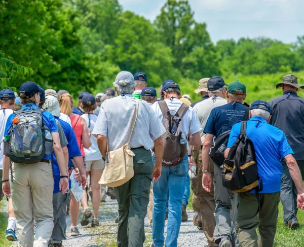 A large group of adults touring a battlefield, walking away from the camera.