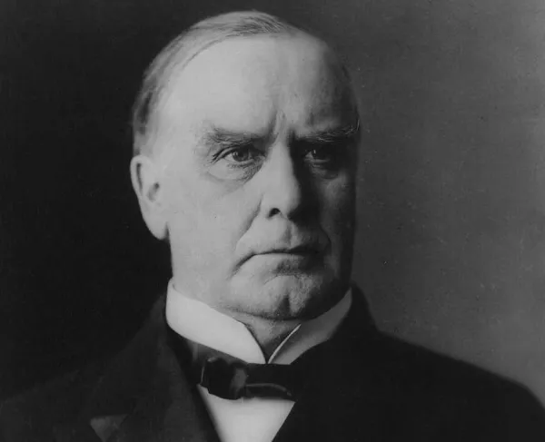 Black-and-white head-and-shoulders portrait of President William McKinley wearing a dark suit and bow tie, shown in profile facing right.