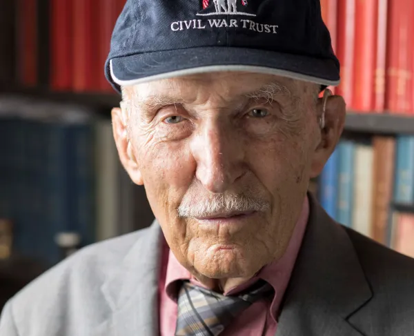 Older man wearing a Civil War Trust baseball cap, gray jacket, red shirt, and plaid tie.