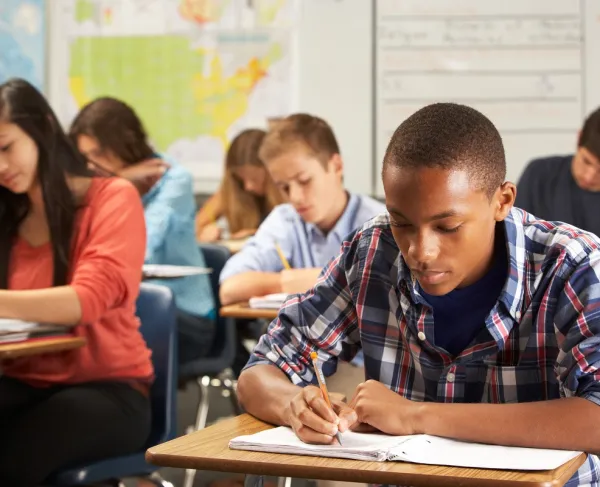 This is an image of high school students taking a test while sitting at their classroom desks. 