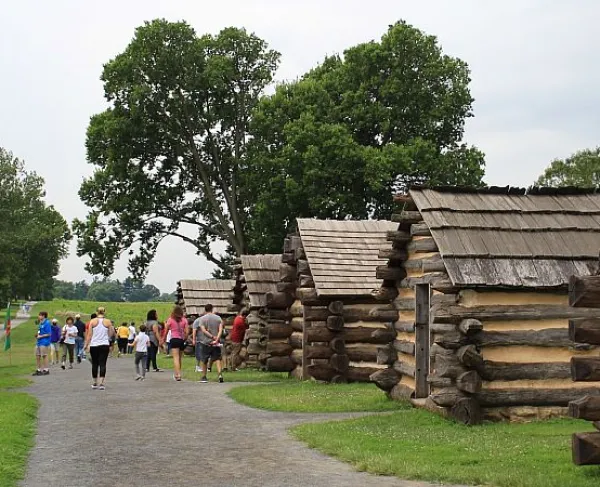 People walking down a path between log cabins