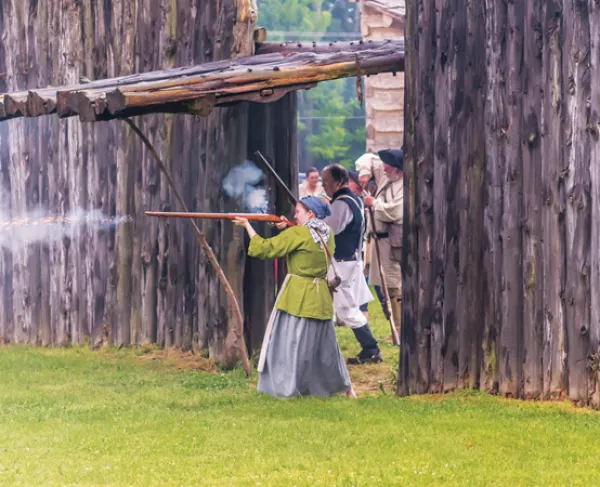 This is an image of a woman firing a gun at Logan's Fort. 