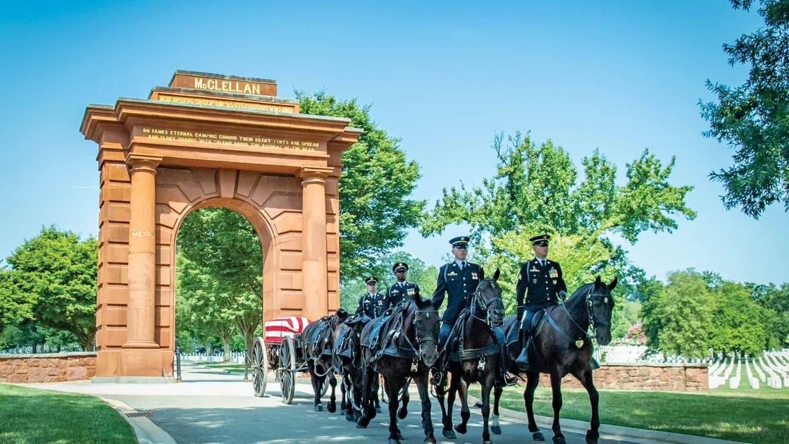 A funeral service passes through McClellan Arch at Arlington National Cemetery, Arlington, Va.