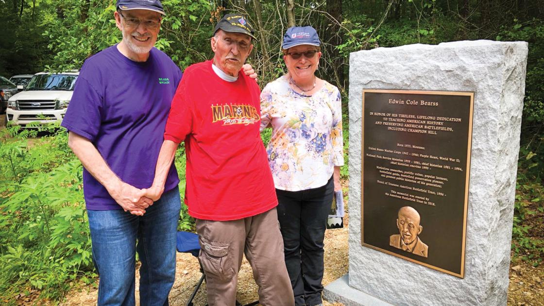 Ed Bearss (center) stands between a couple next to a granite monument dedicated to him