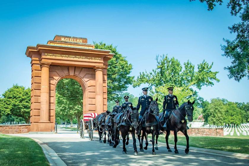 A funeral service passes through McClellan Arch at Arlington National Cemetery, Arlington, Va.